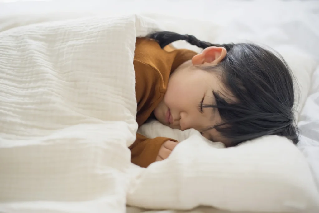 Child sleeping under a white blanket