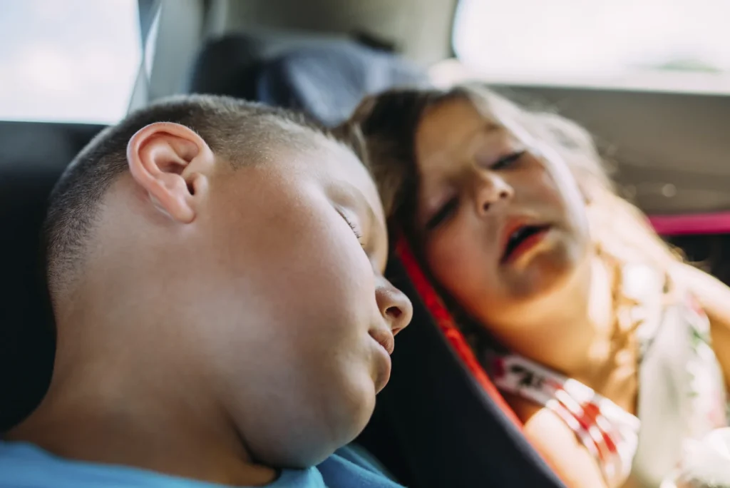 Two children sleeping in a car
